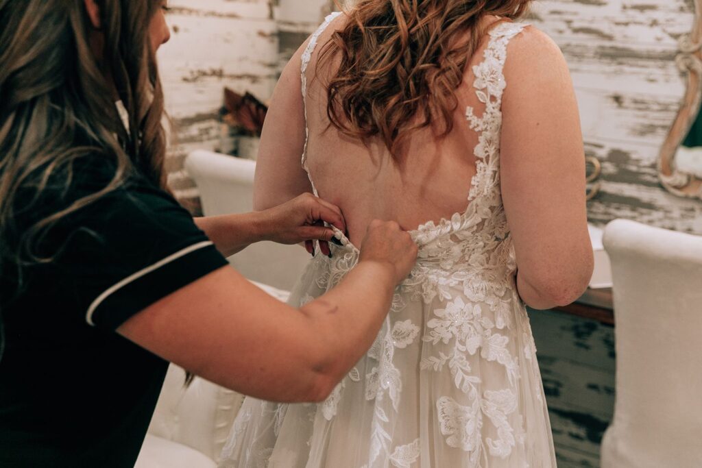 mother assisting the bride into her wedding dress