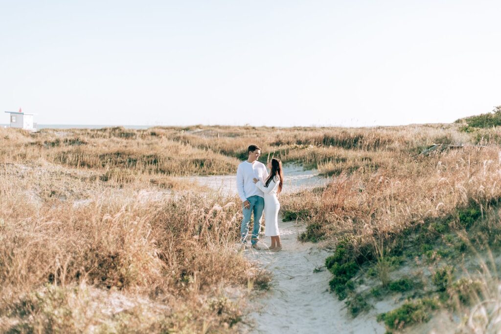 engaged couple stands in sand dunes