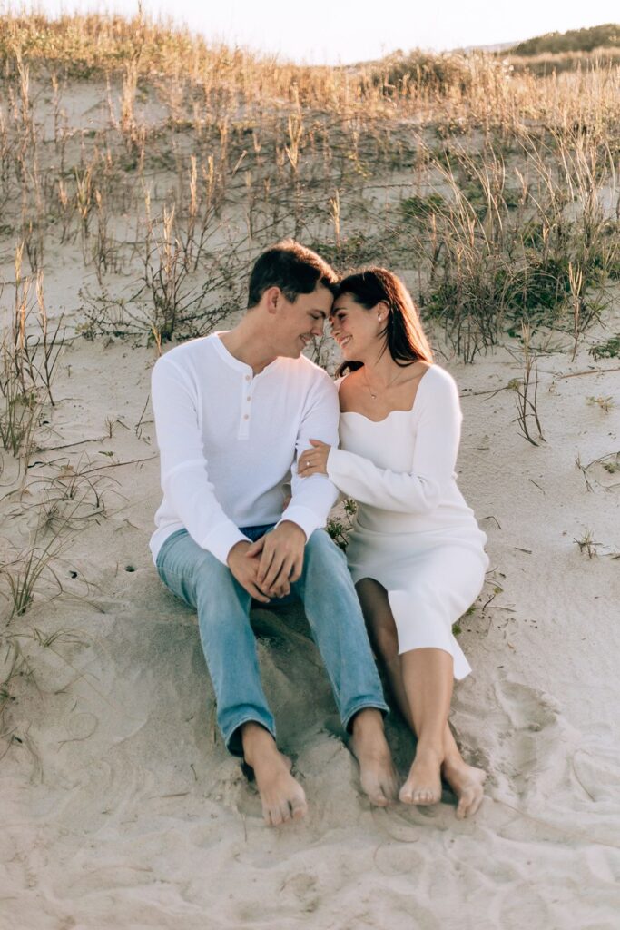 engaged couple sit on the sand dunes at jetty park cocoa beach